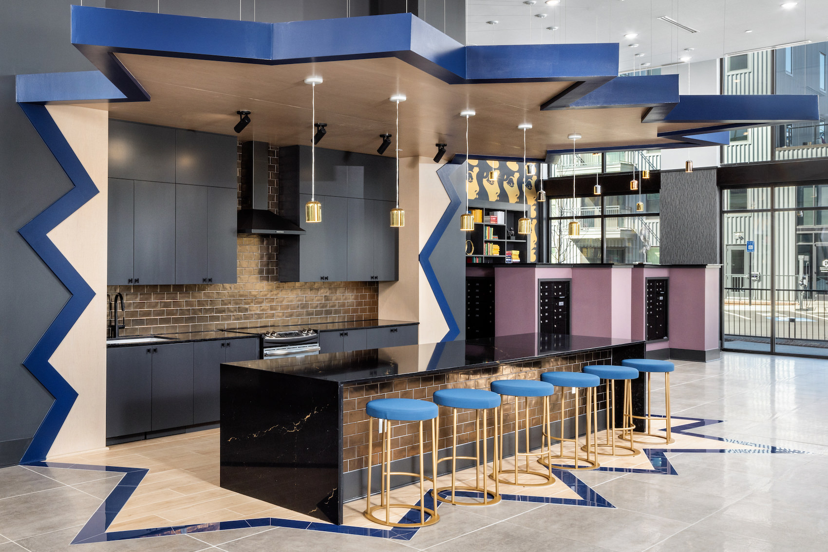 demonstration kitchen with seating, overhead lighting and in close view of the resident library and mailroom