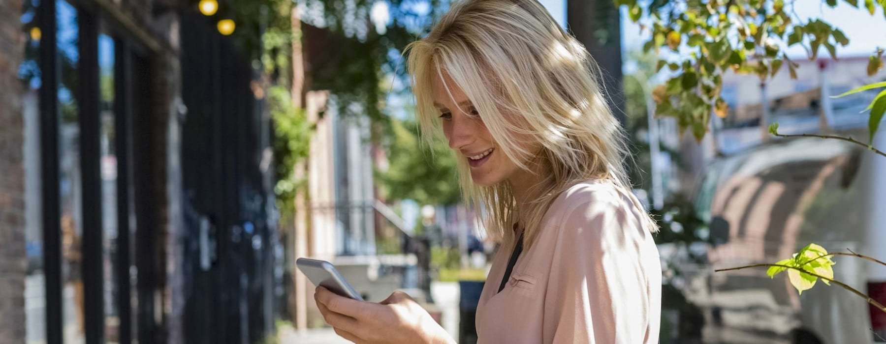 a woman on a sidewalk looking at a cell phone