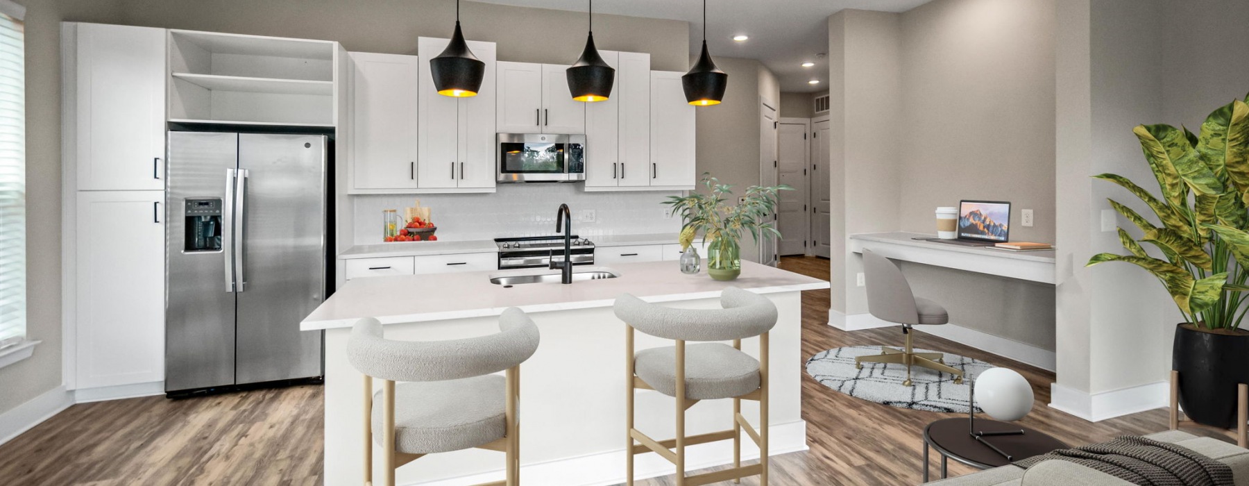 kitchen with white cabinets and island with stools beneath three pendant lights