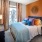 Model bedroom at our apartments in Atlanta, featuring grey carpet, a rust colored wall, and colorful decor. 