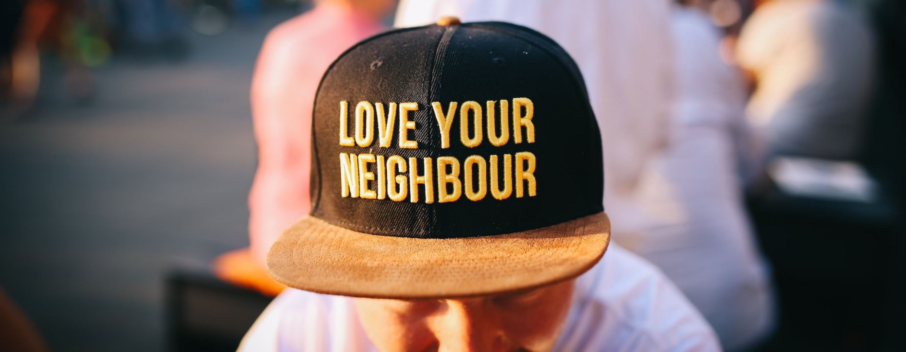 man in black and yellow hat that says Love Your Neighbor